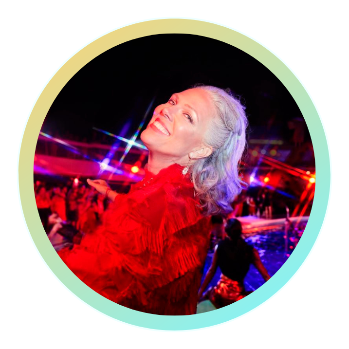 A woman strikes a pose on the pool deck, illuminated by red lights during Scarlet Night on a Virgin Voyages cruise ship